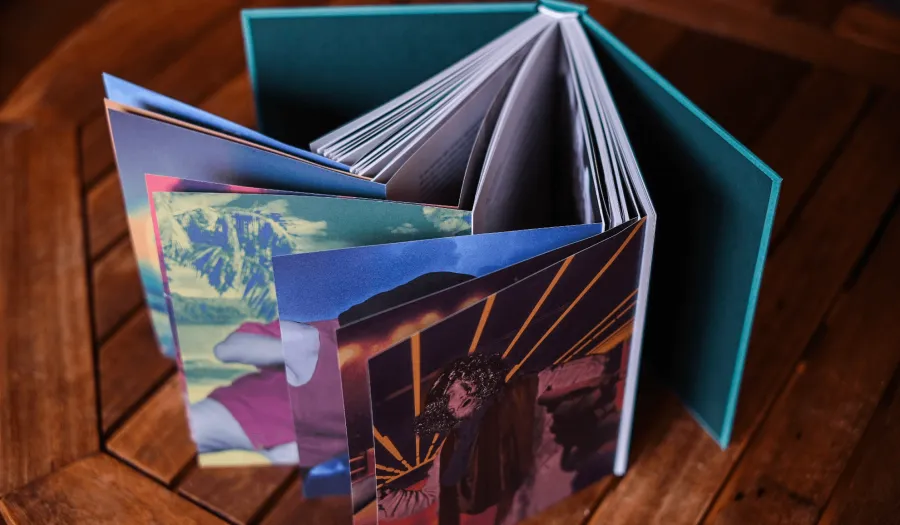 The book standing open on a wooden table, pages curling