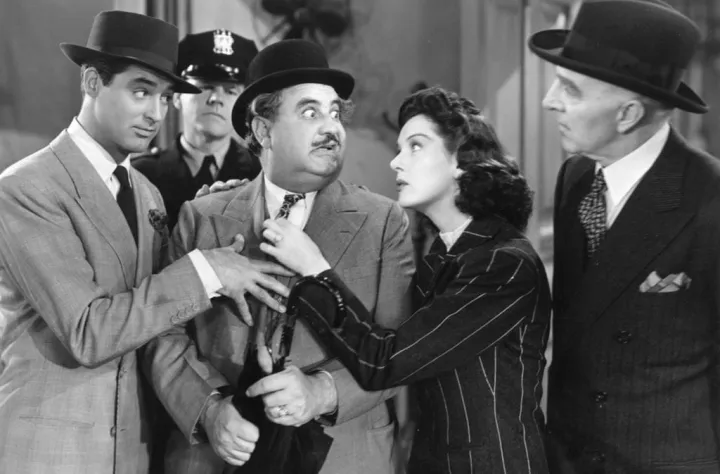 A screwball comedy still: a crowded argument between men in suits and hats