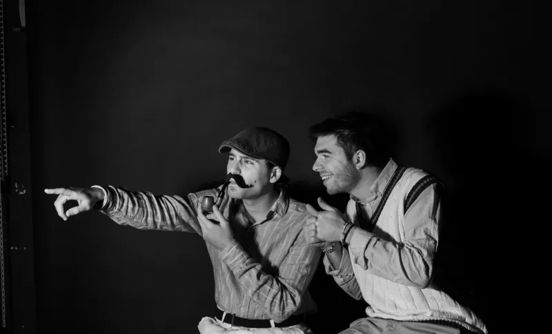 Two men pointing, photographed in the studio against black