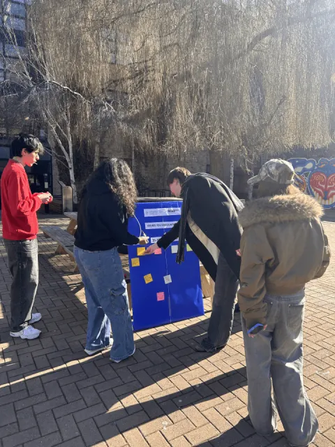Passers-by stopping to add notes to the research board