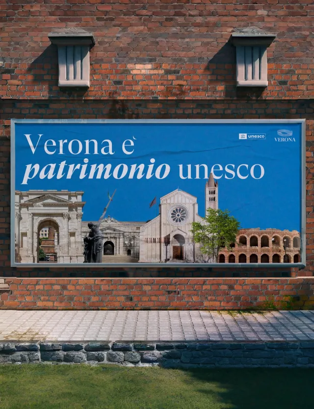 A Verona è patrimonio UNESCO billboard on a brick wall above a lawn