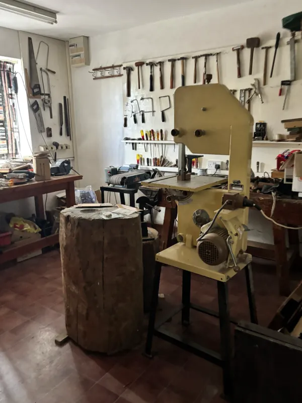 A shared workshop with a bandsaw, workbenches and tools on the wall