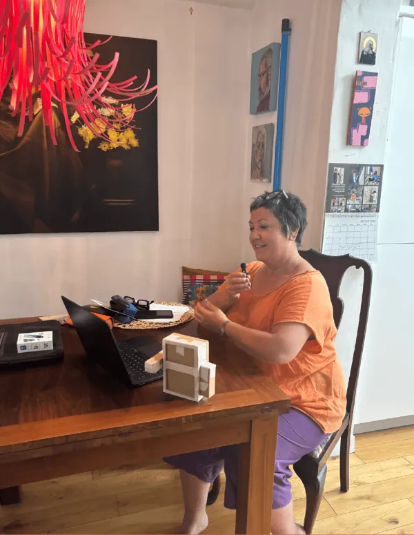 A maker at her kitchen table talking to the dock, a laptop beside her