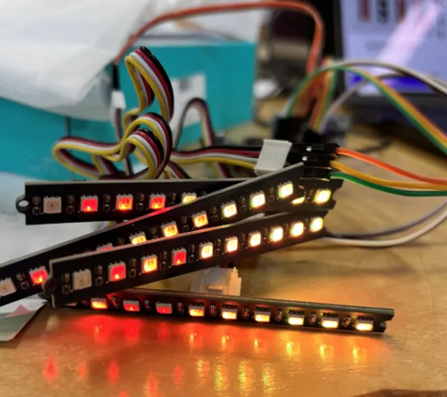 Four addressable LED strips on a bench, fading from red to amber