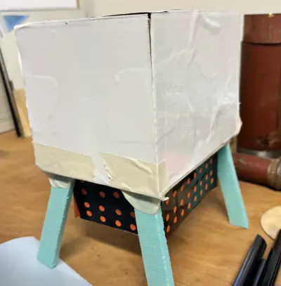 Paper-and-tape volume study standing on turquoise 3D-printed legs