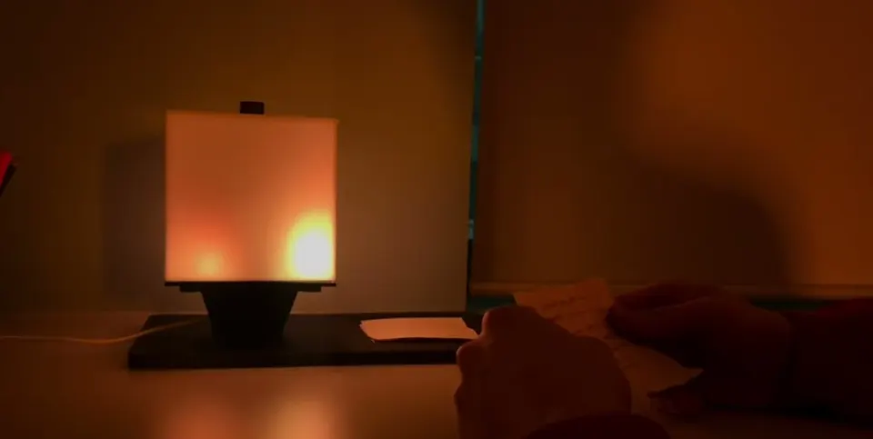 NOX glowing on a desk while a hand writes on a slip of paper