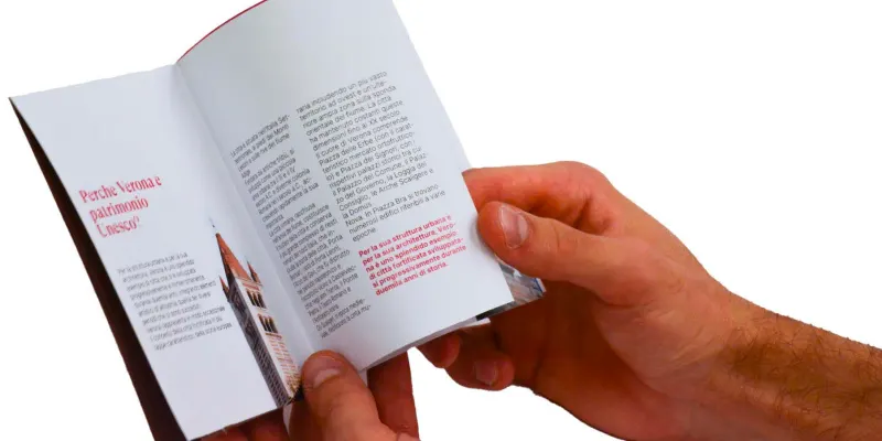 Hands holding the brochure open on a text spread