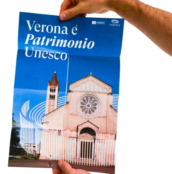 The brochure unfolded into a poster of San Zeno, held up by two hands