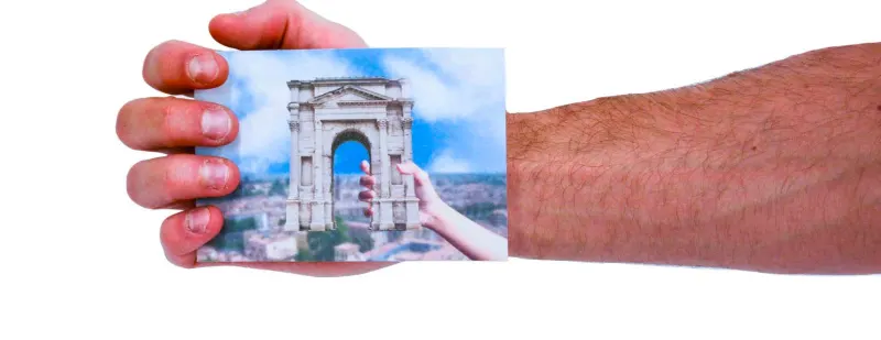 A hand holding a postcard of the Arco dei Gavi