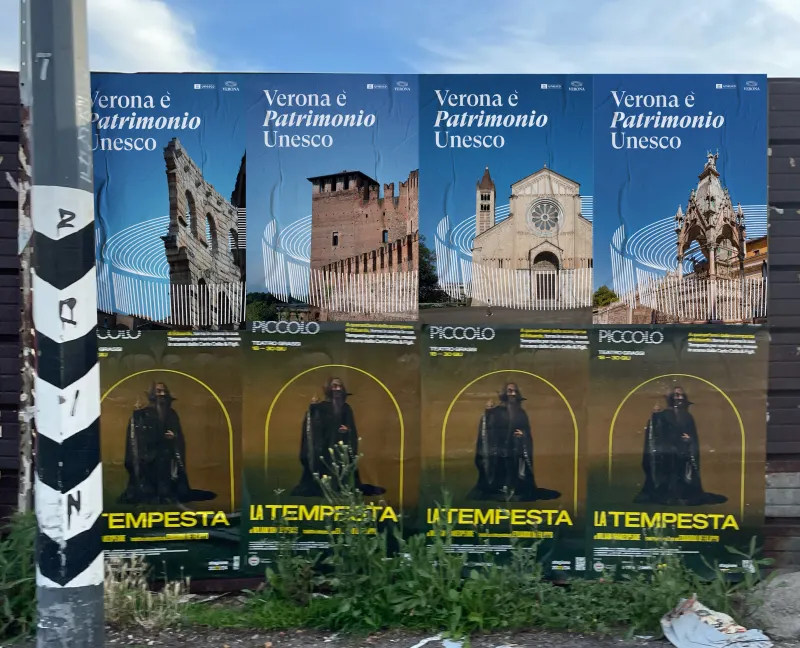 A row of Verona UNESCO event posters pasted on a street hoarding