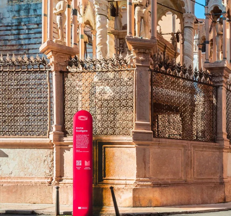 A crimson monumental totem beside the Arche Scaligere