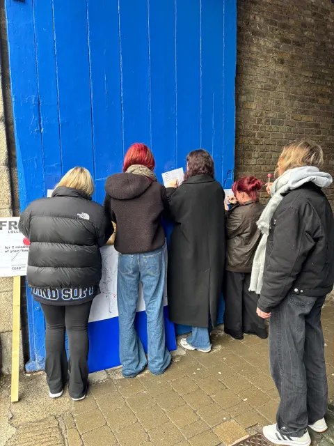 Five people crowding around the probe taped to a blue door on a Dublin street